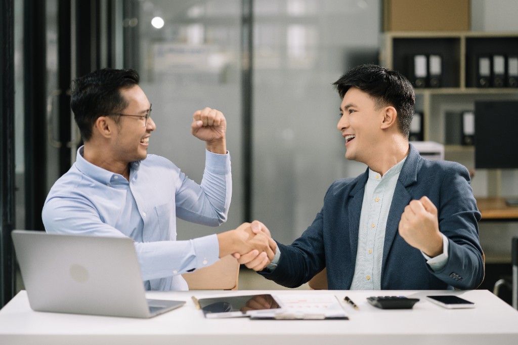 Two Indian businessmen celebrating a successful hire with a handshake in a modern office — recruitment agency Mumbai